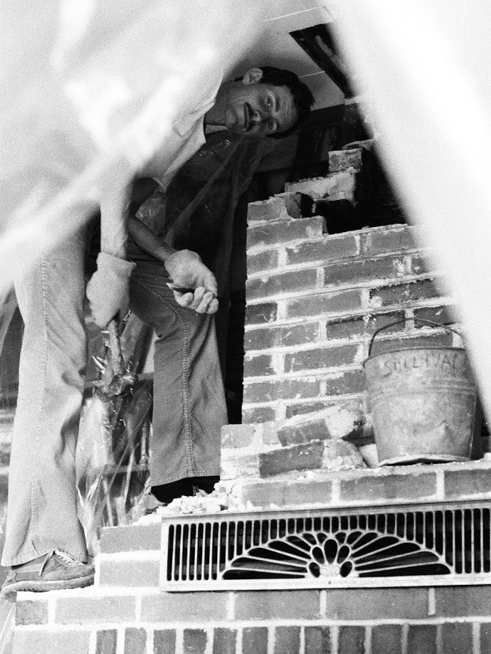 Image 3: Steve is partially hidden by plastic (used to contain dust) as he continues to remove bricks from the fireplace.