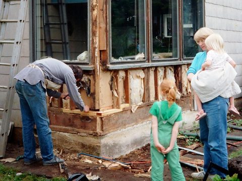 Dave repairs rotten walls below the front windows while Mary, Molly and Janet watch.