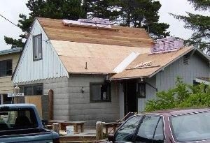 Getting started: By the time this picture was taken on day two, Bill and I had already stripped off the old roof and begun applying plywood. Also, a delivery truck had dropped off all the necessary shingles on the roof -- a real time-saver.