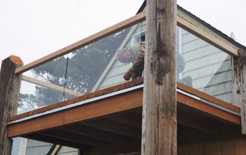 Cedar railings are installed along with plate glass.